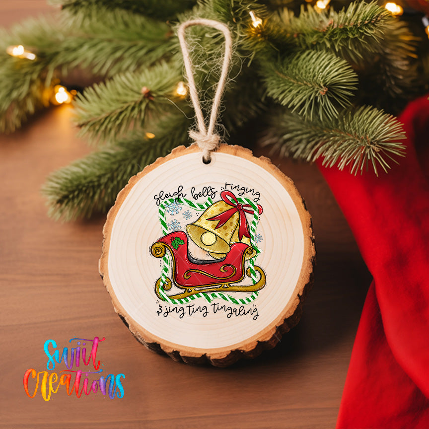 A wooden ornament with a bell and a sled, hanging on a Christmas tree.