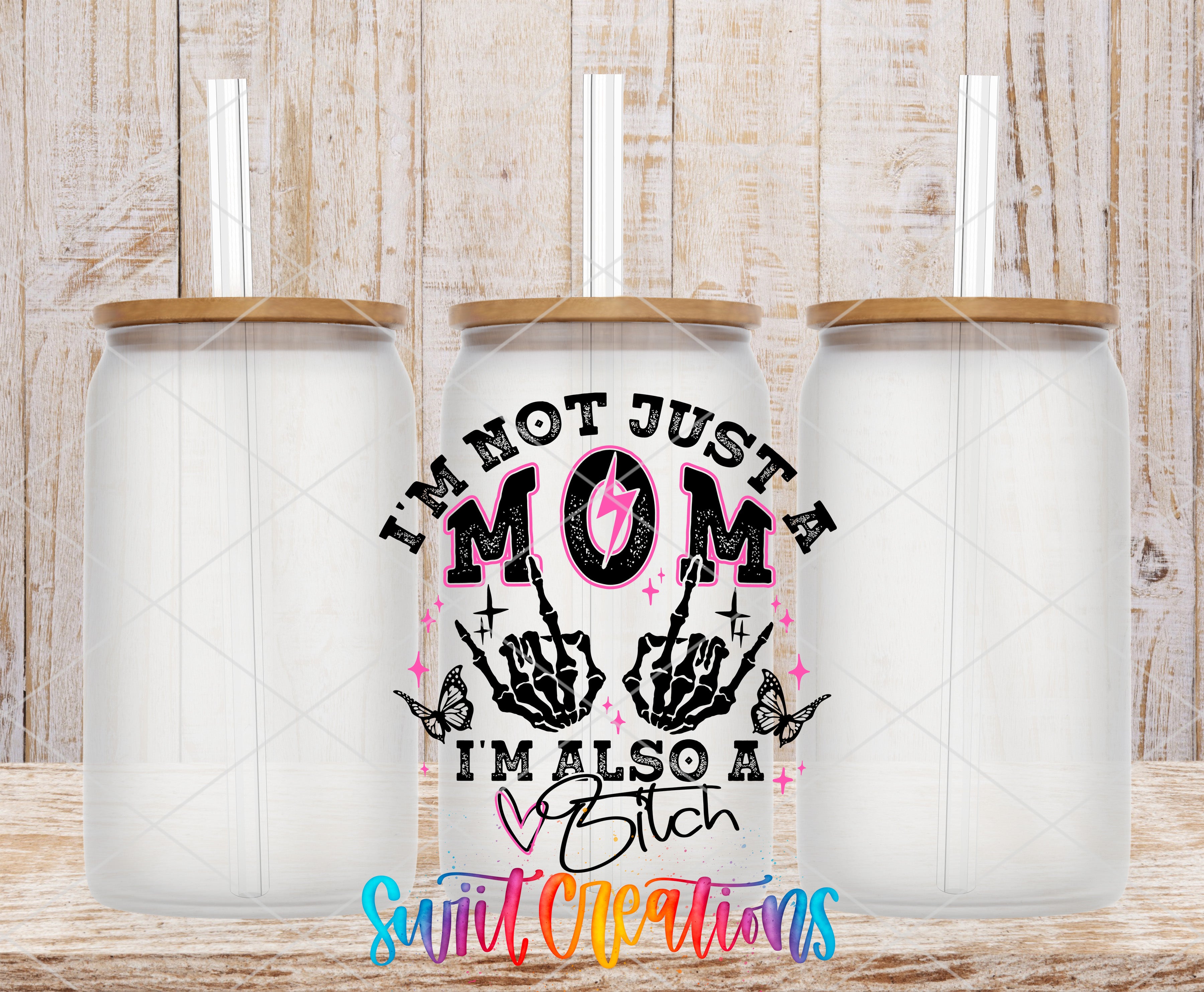 three clear glass jars with lids, arranged in a row against a wooden background. The jars have a unique design with a text and graphic element that reads "I'm not just a mom, I'm also a bitch" and includes a skeleton hand and butterflies.
