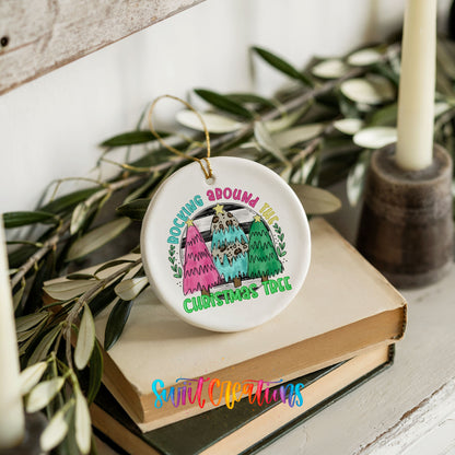 A white ceramic ornament with a colorful design hangs on a stack of books, surrounded by greenery.