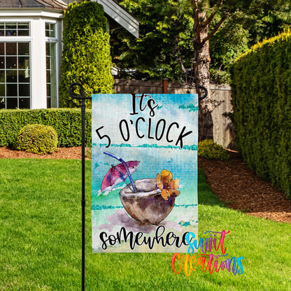 A colorful garden sign with the text "It's 5 o'clock somewhere" and an illustration of a cocktail glass with a flower.