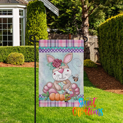 A colorful garden sign featuring a cartoon rabbit and a bee, with a floral border and text that reads "Sweet Creations".