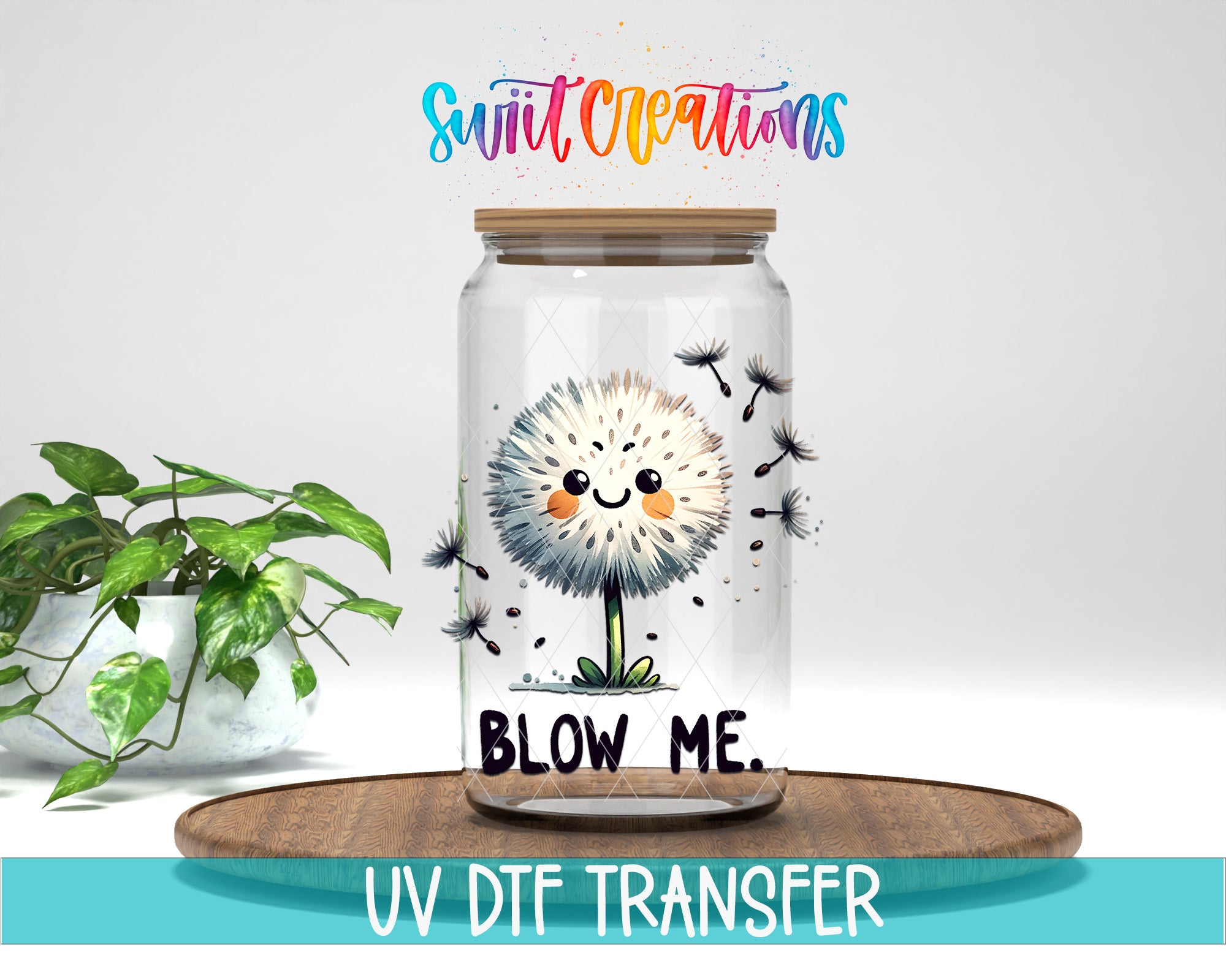 A glass jar with a cartoon dandelion design and the text "BLOW ME" inside, placed on a wooden surface next to a potted plant.