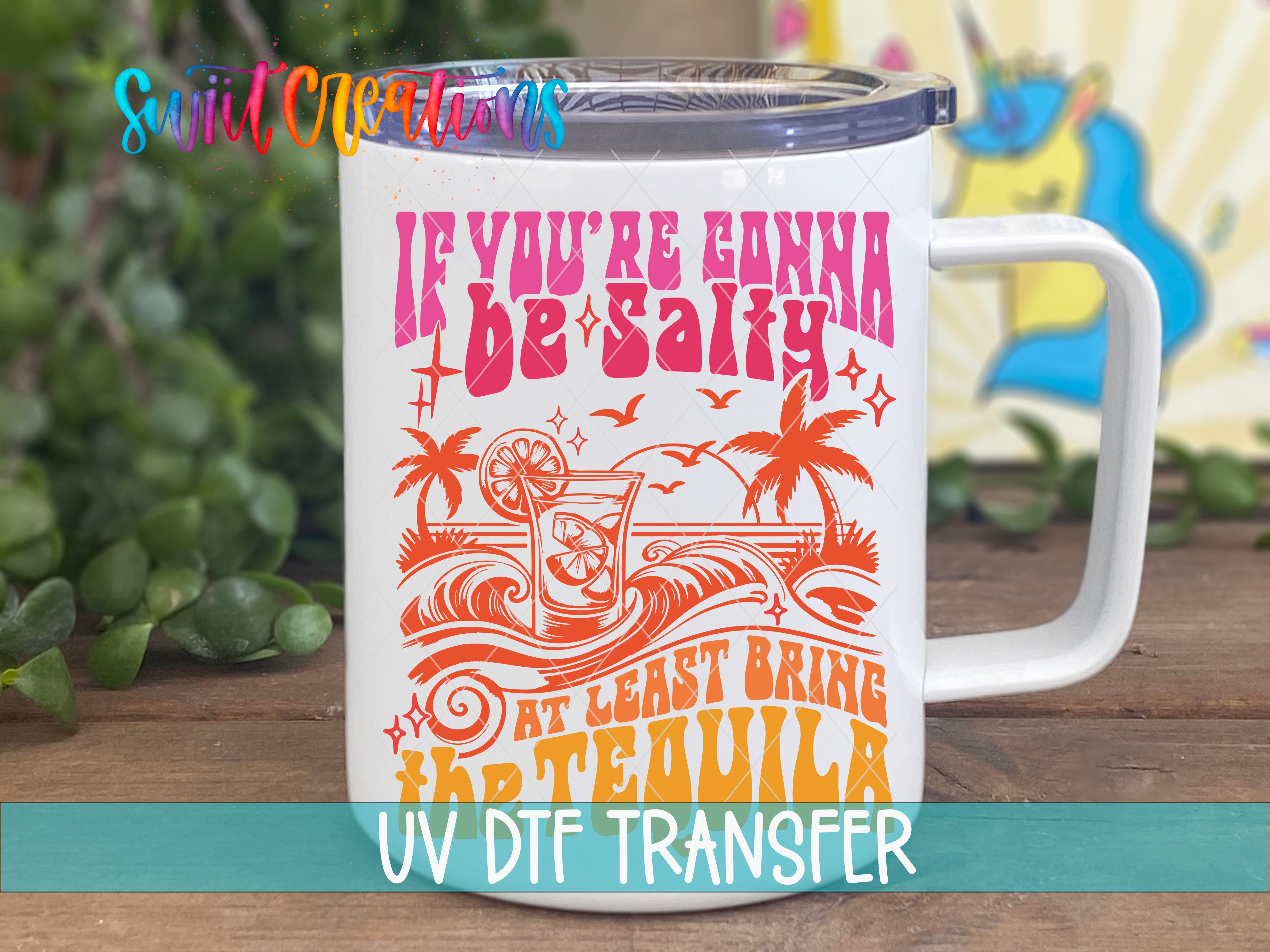 A white mug with a colorful design and text printed on it, placed on a wooden surface.