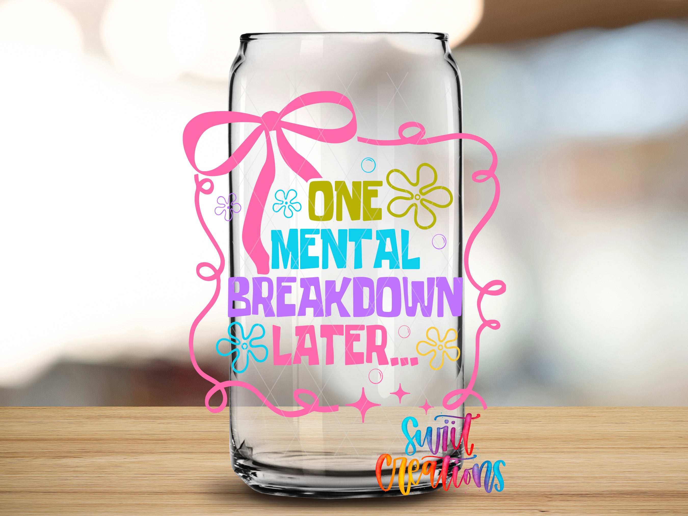 a glass jar with a colorful design and text on it, placed on a wooden surface.