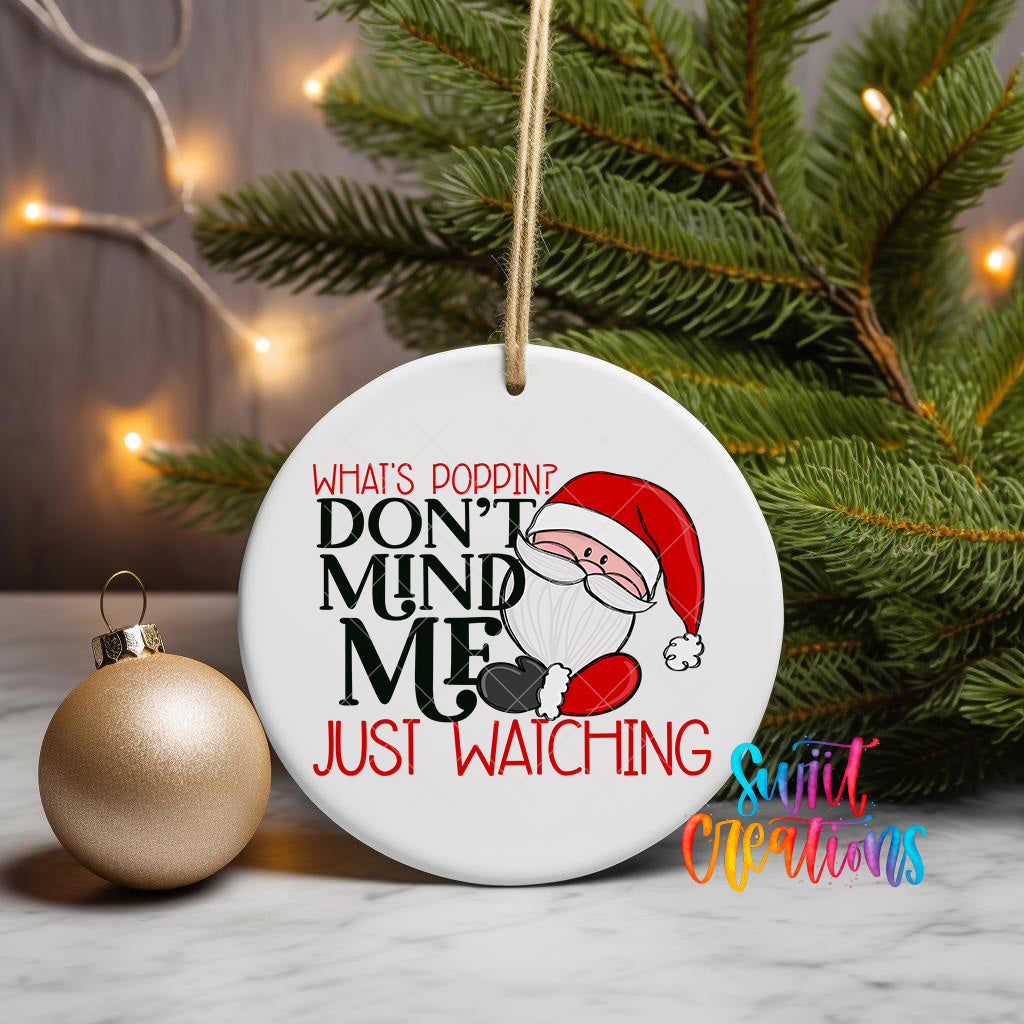A white ornament with a Santa Claus design and text that says "What's Poppin' Don't Mind Me Just Watching" is displayed on a Christmas tree.