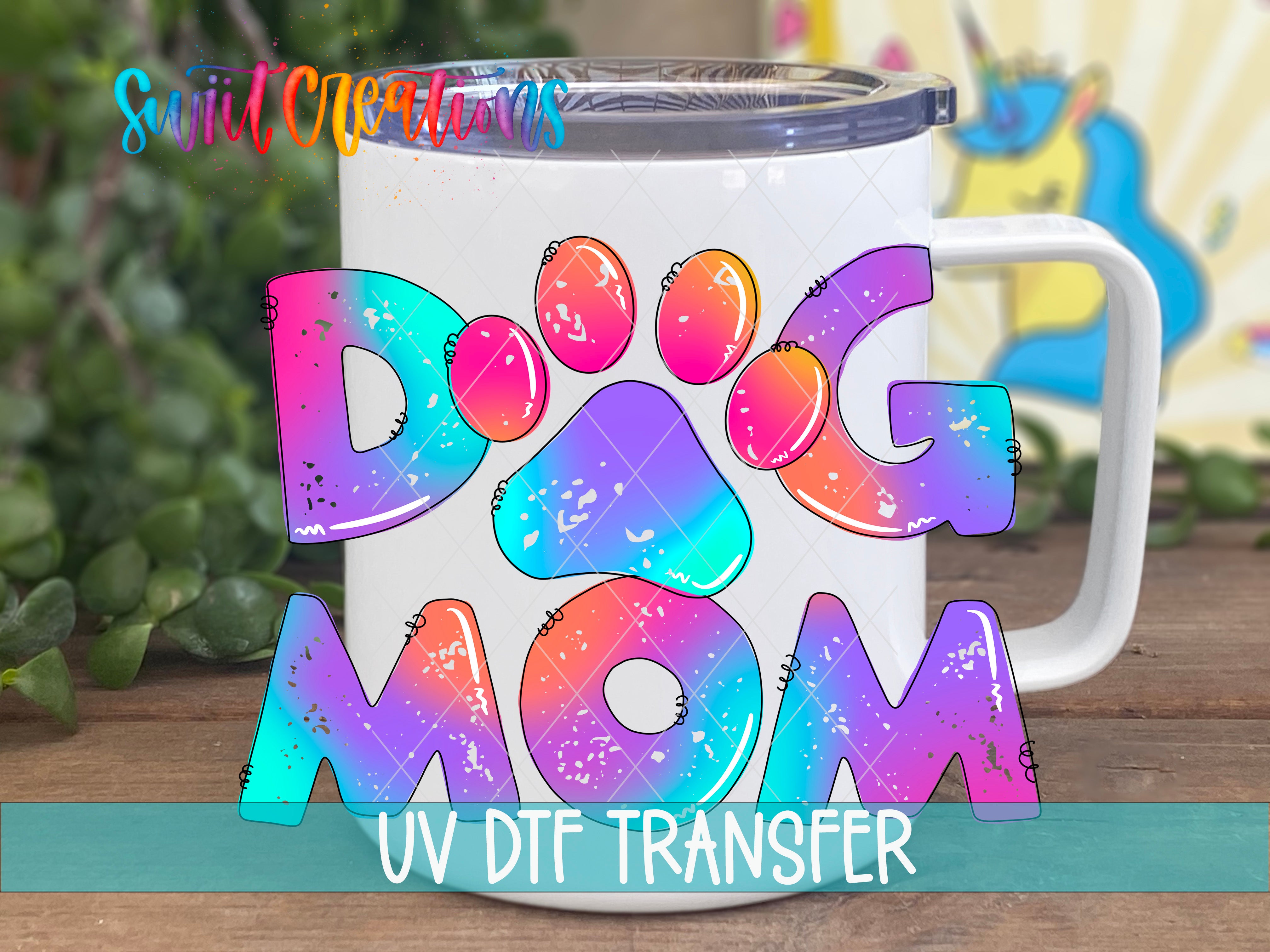 A white mug with colorful text that says "DOG MOM" in a rainbow-colored style.