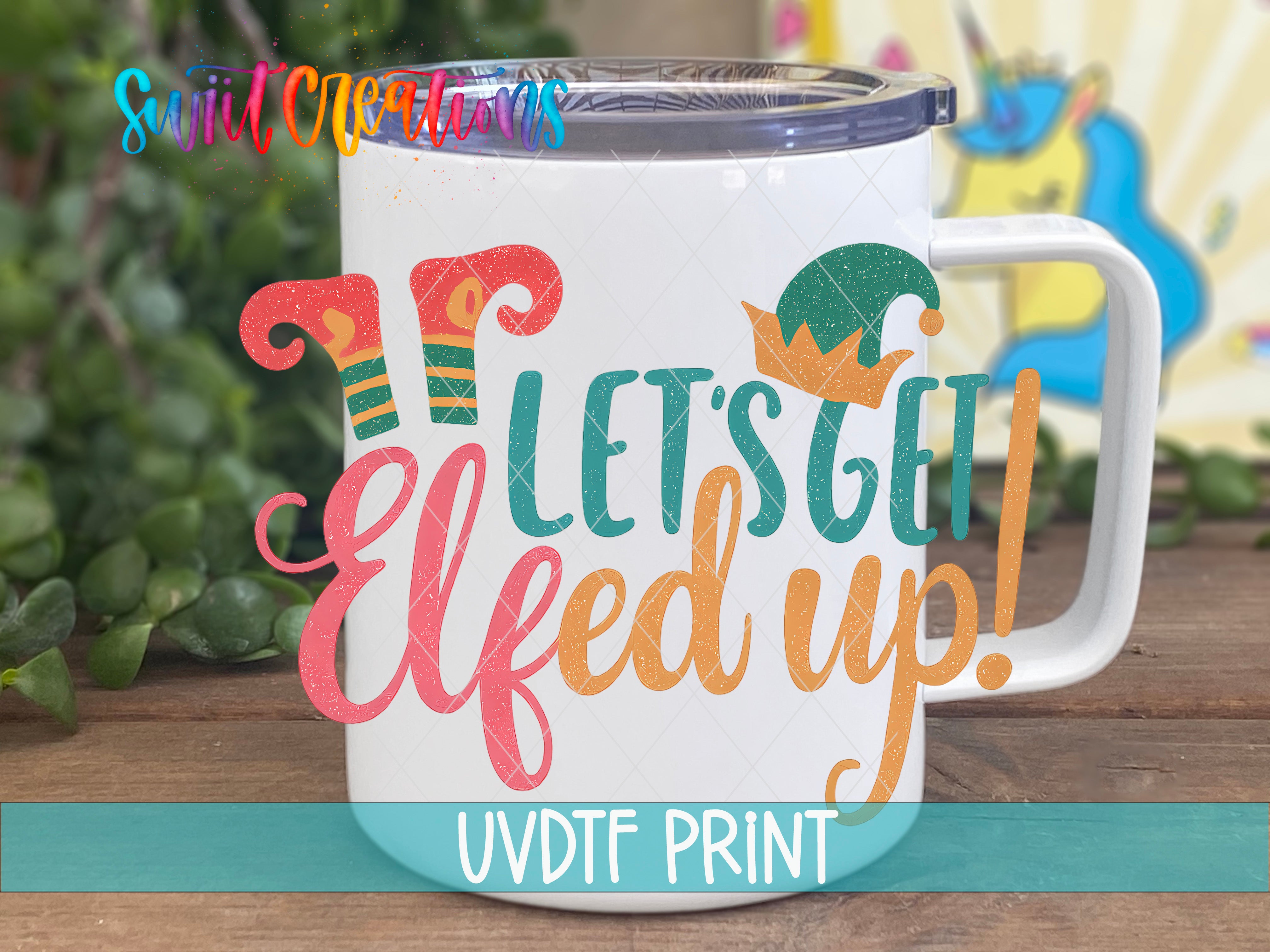 A white mug with a colorful design featuring a cartoon elf and the text "Let's get Elfed up!"