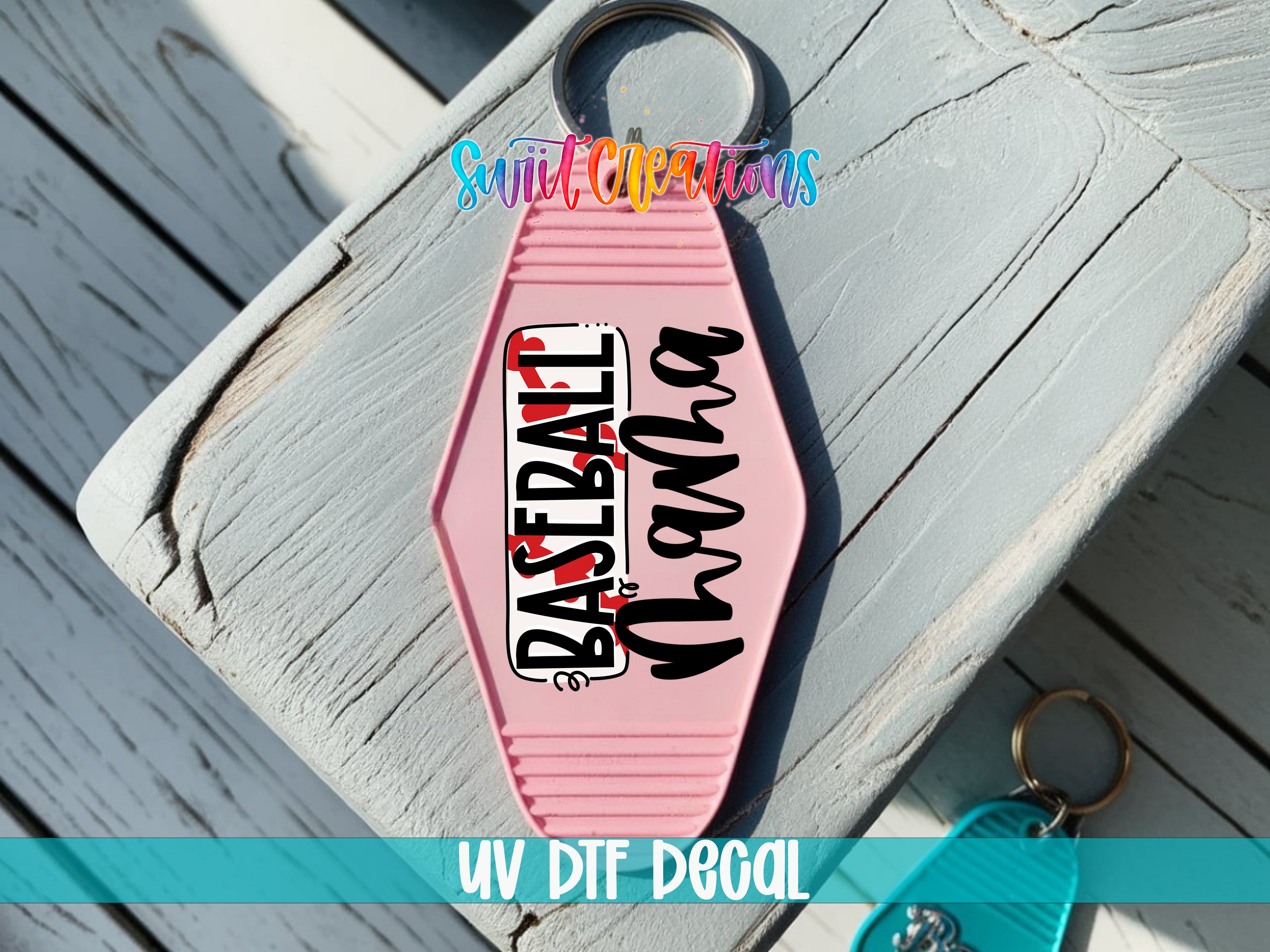 A pink keychain with the text "Baseball" printed on it, placed on a wooden surface.