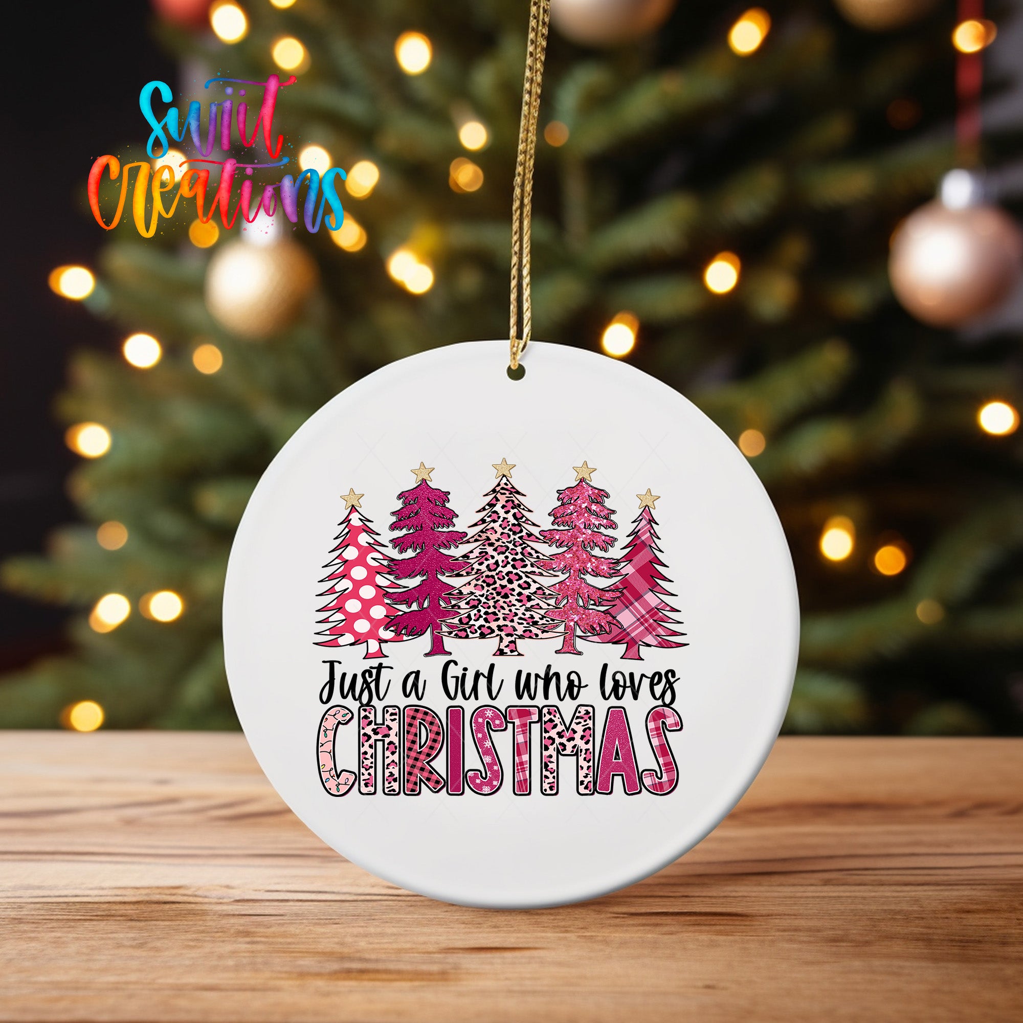 A white Christmas ornament with a design of pink and leopard print trees, and the text "Just a girl who loves Christmas" hanging from a string.