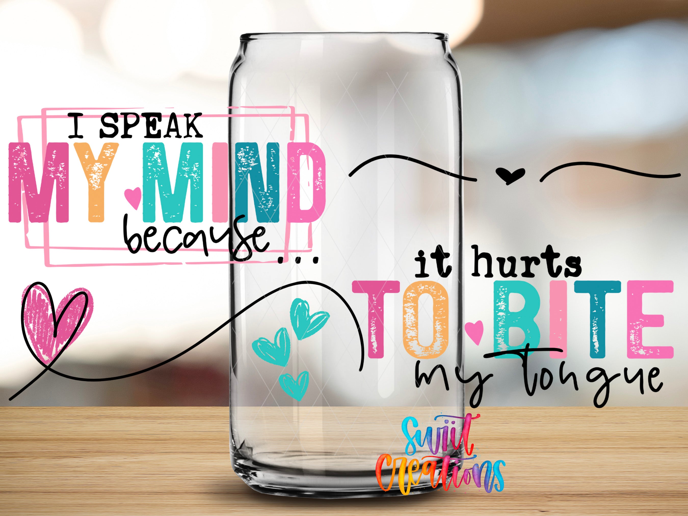 a clear glass can with colorful text and heart-shaped designs on it, placed on a wooden surface.
