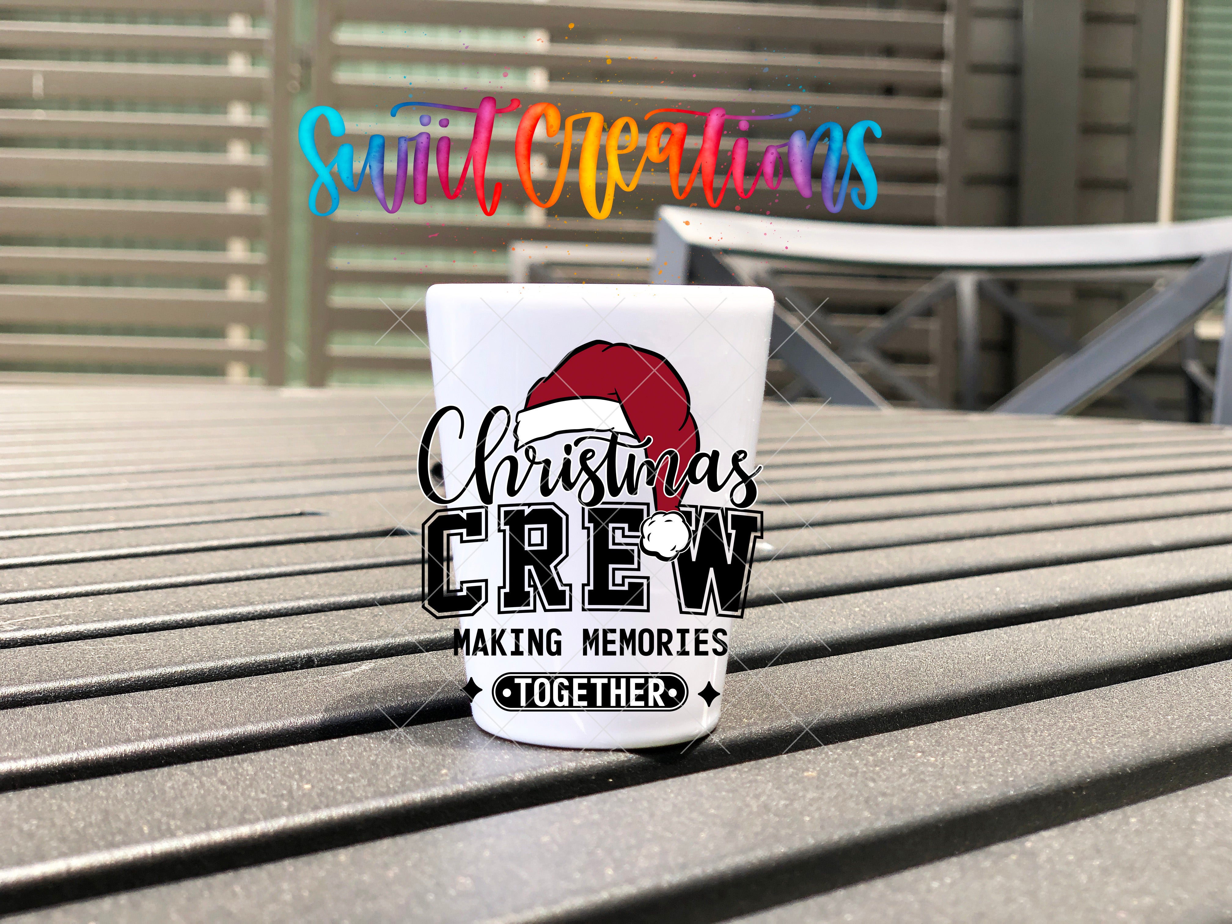 A white mug with a red Santa hat and the text "Christmas Crew" printed on it, sitting on a wooden surface.