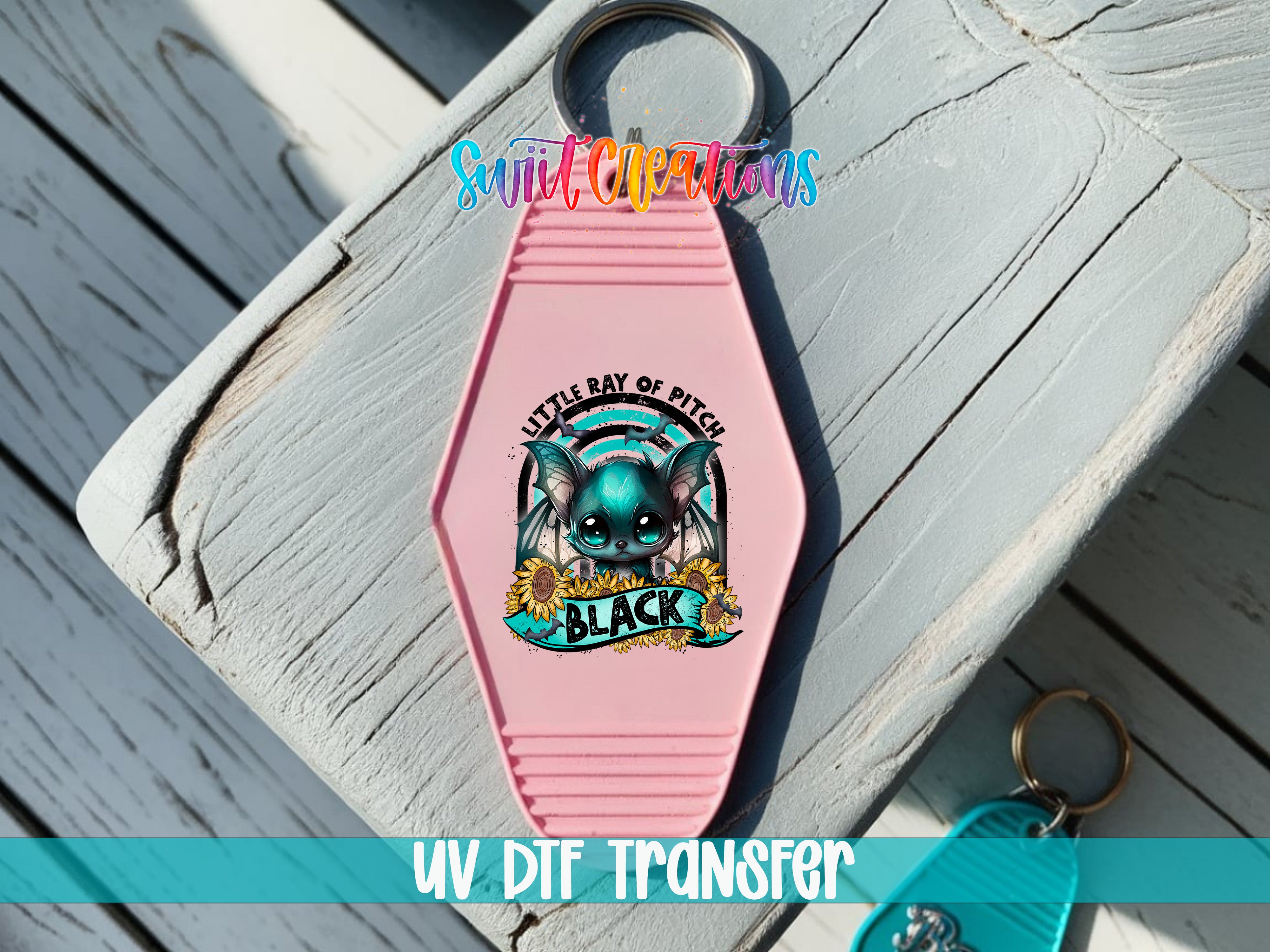 A pink keychain with a cartoon character and text, placed on a wooden surface.