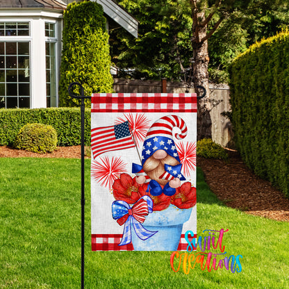 A patriotic-themed garden flag featuring a gnome holding an American flag and flowers, set against a backdrop of a house and trees.