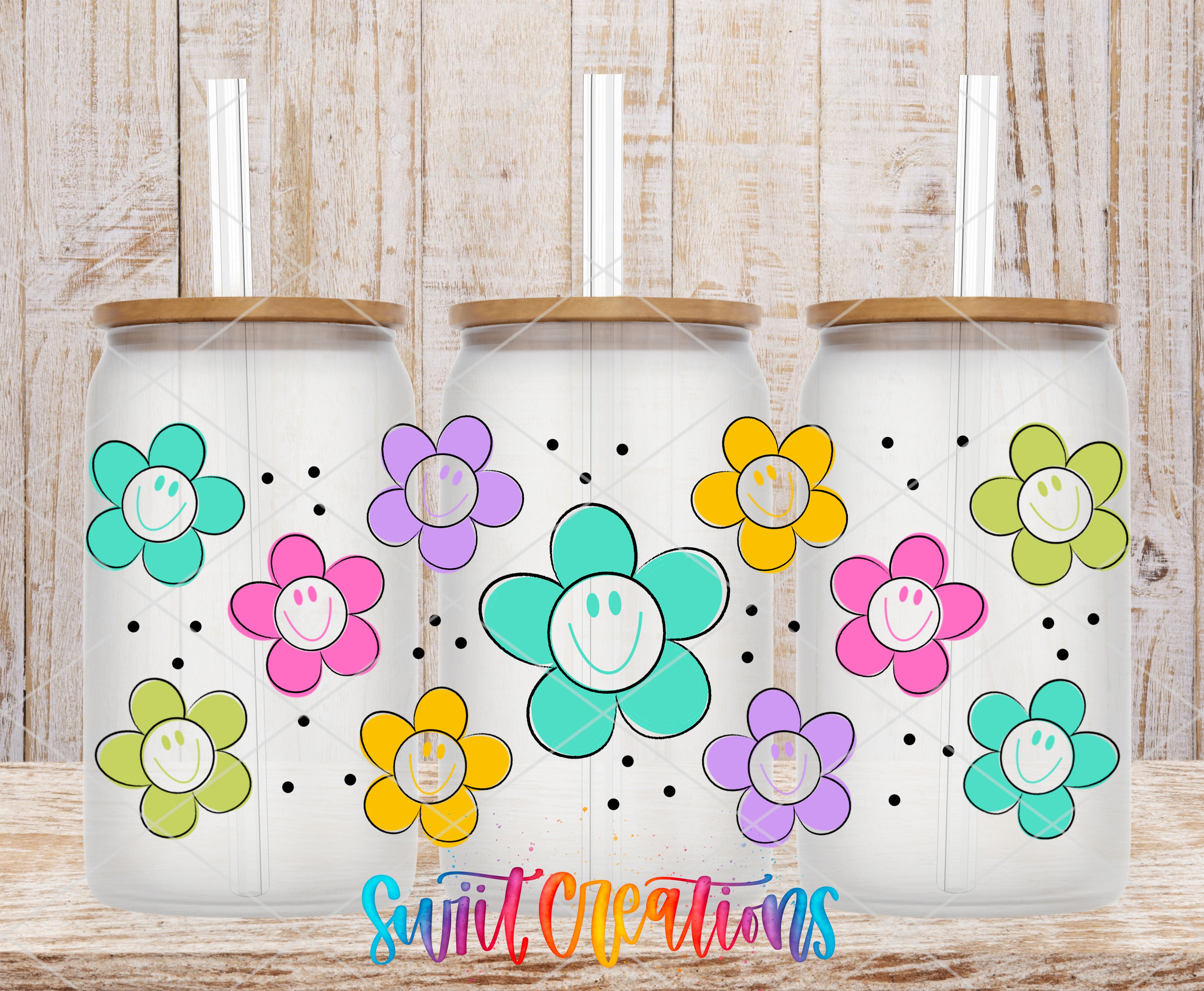 Three glass tumblers with flower designs on them, placed on a wooden surface.