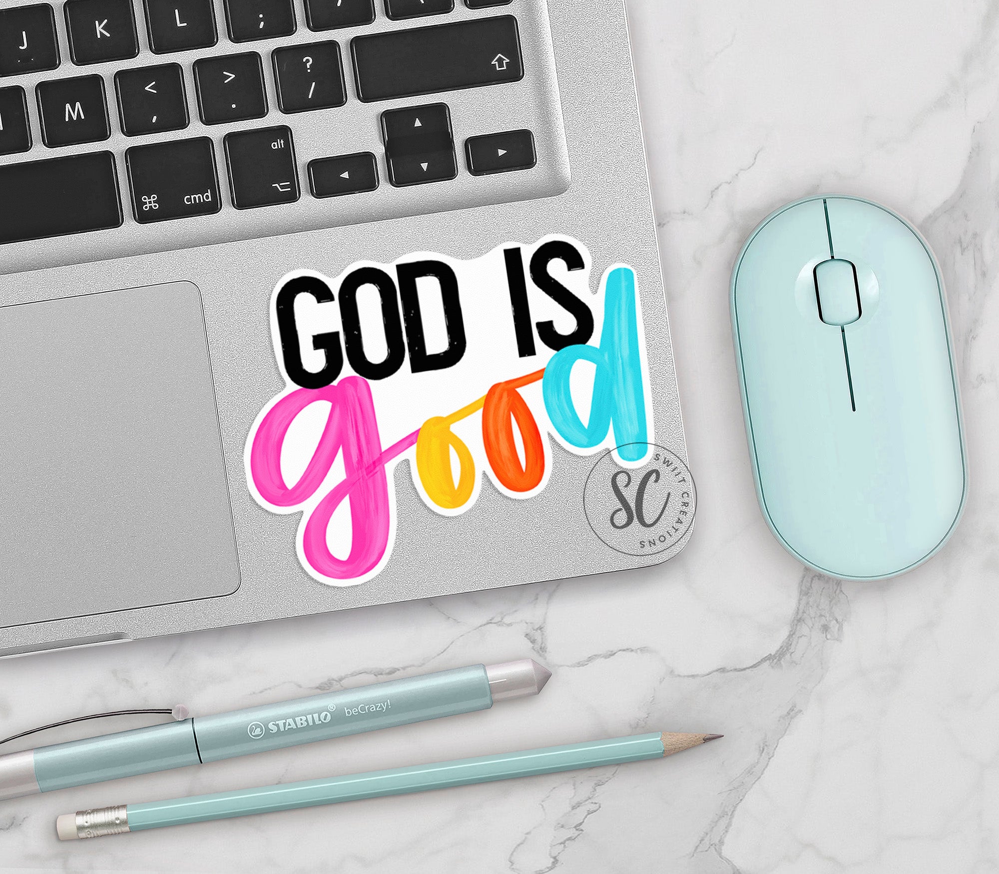 a laptop with a sticker that says god is good next to a mouse
