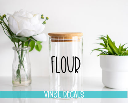 a glass jar with a wooden lid sitting next to a vase with flowers