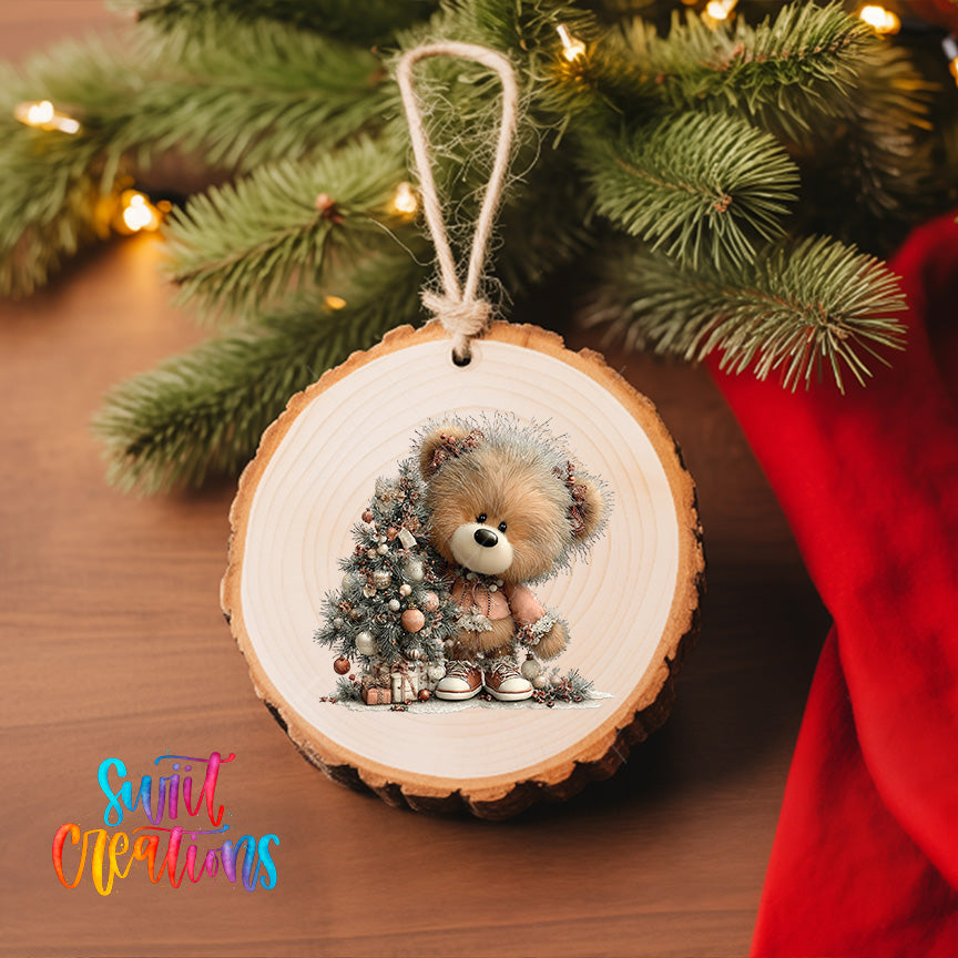 A wooden ornament featuring a teddy bear is hanging on a Christmas tree, surrounded by pine branches and twinkling lights.