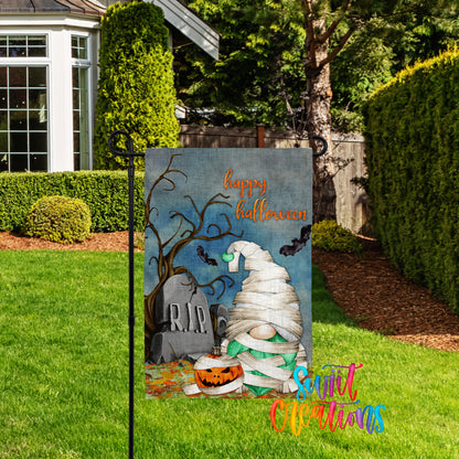 A Halloween-themed garden sign featuring a gnome, a pumpkin, and a gravestone, with the text "Happy Halloween" displayed on the sign.