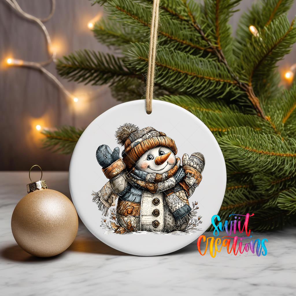 A white ceramic ornament featuring a snowman is displayed on a table, with a gold ornament and a Christmas tree in the background.