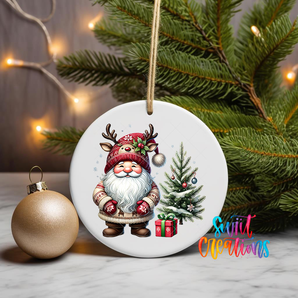 A white ceramic ornament featuring a smiling gnome wearing a red hat and holding a present, with a Christmas tree and ornaments in the background.