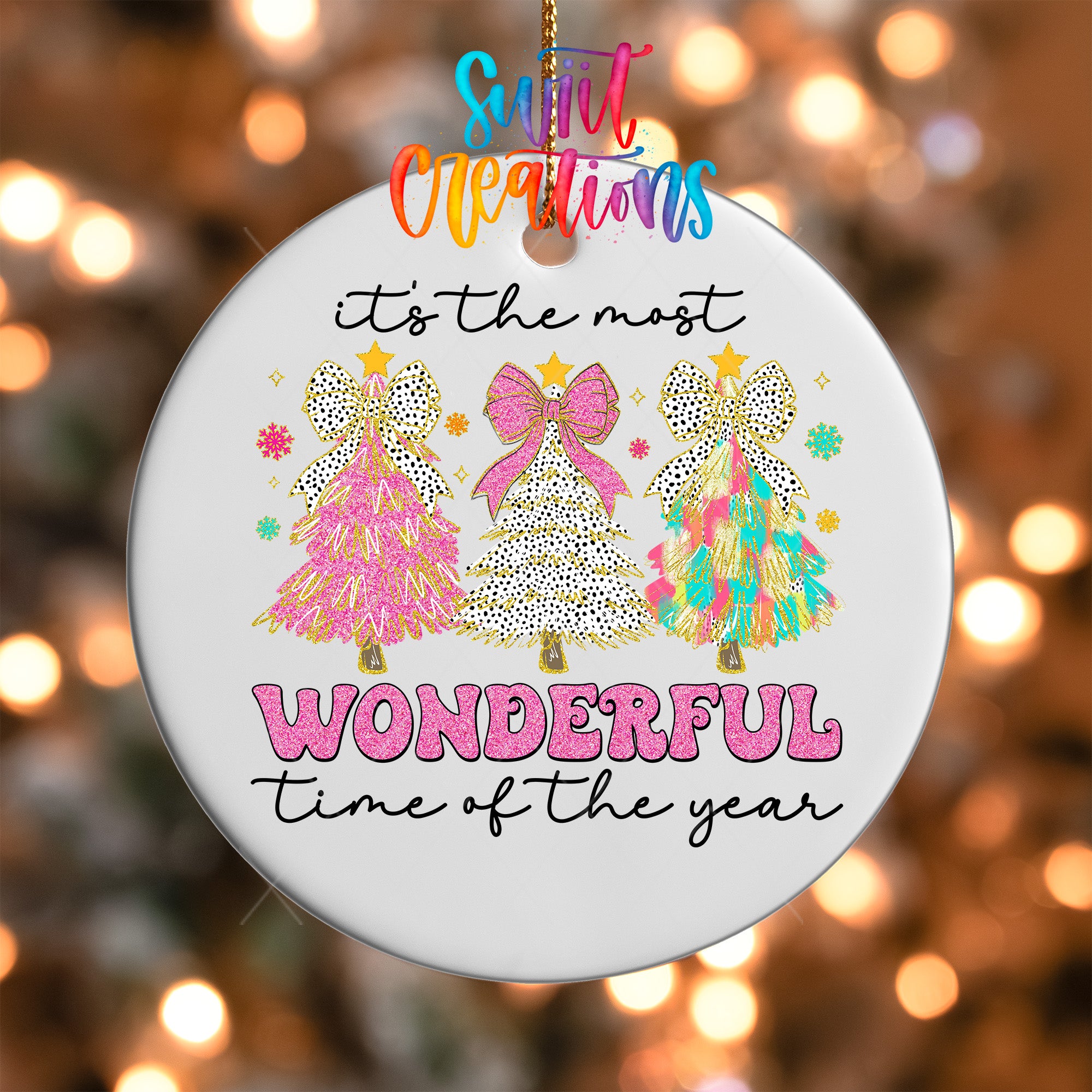 A white ornament with a festive design featuring three colorful Christmas trees and the text "It's the most wonderful time of the year" written on it.
