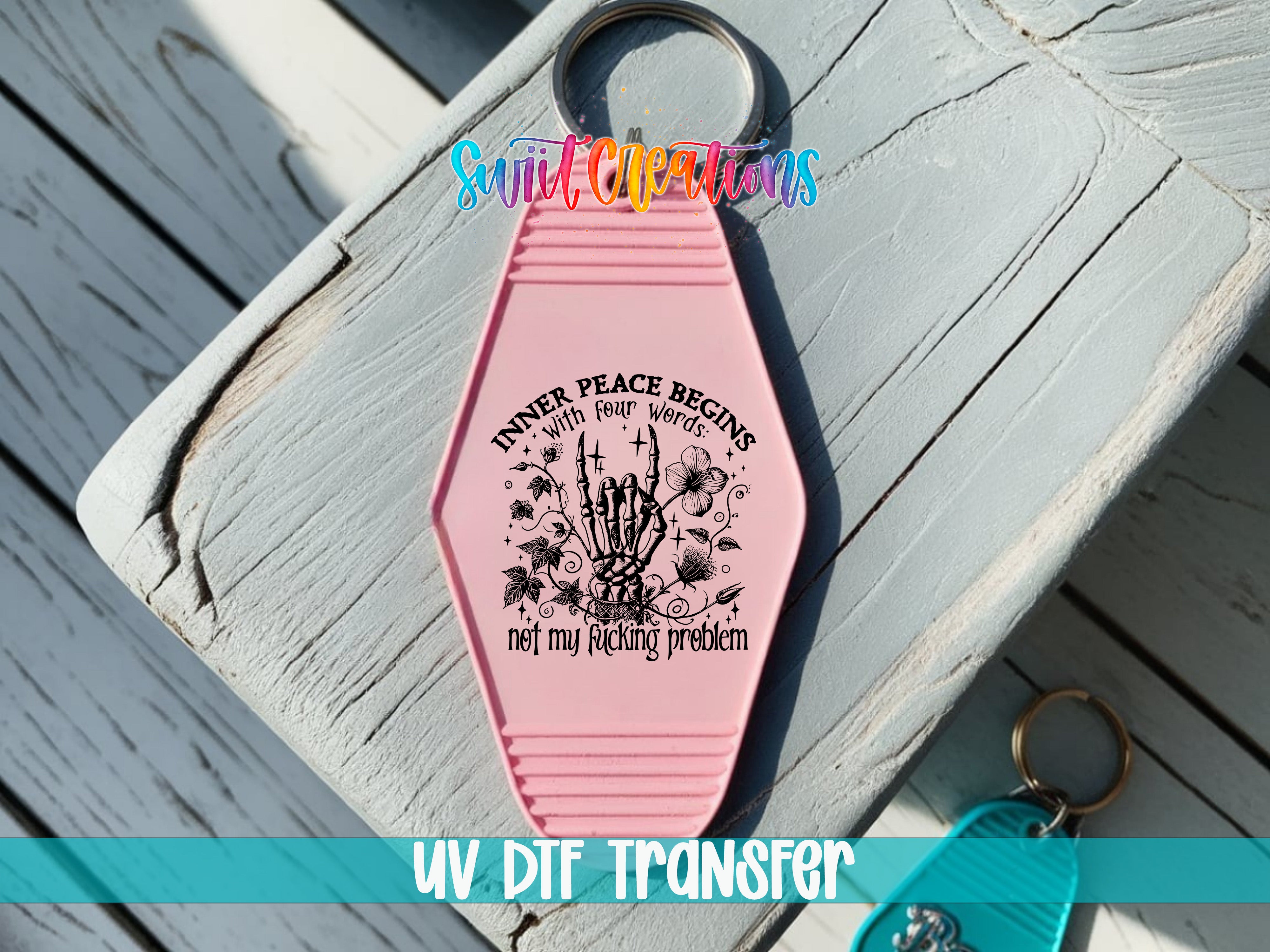 A pink keychain with a graphic design and text on it, placed on a wooden surface.