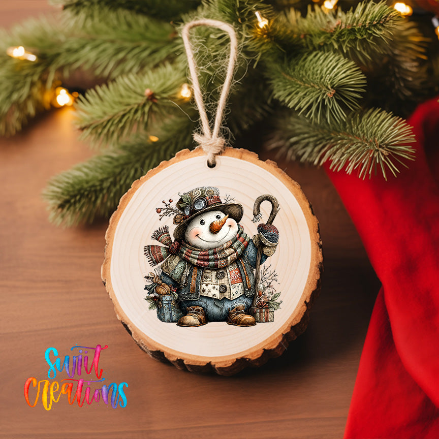 A wooden ornament featuring a smiling snowman is hanging on a Christmas tree, surrounded by pine branches and twinkling lights.