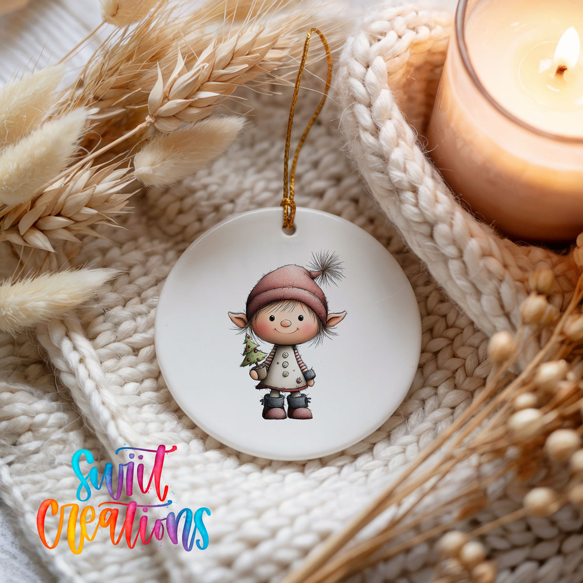 A white ceramic ornament featuring a small elf-like character is displayed on a white knitted blanket, with a lit candle and dried wheat stalks in the background.