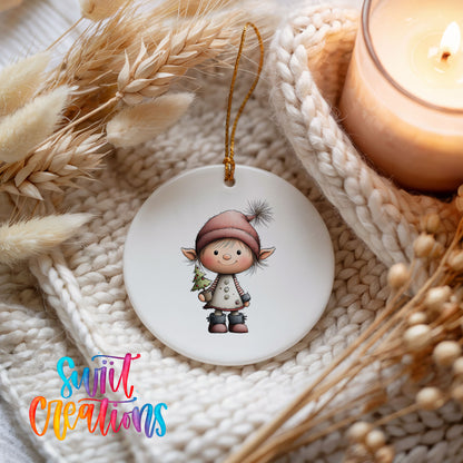 A white ceramic ornament featuring a small elf-like character is displayed on a white knitted blanket, with a lit candle and dried wheat stalks in the background.