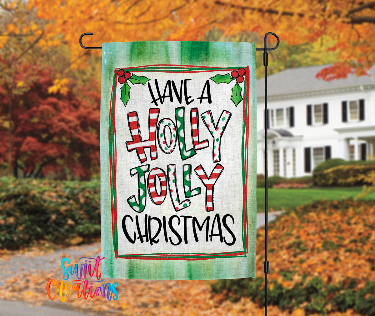 A colorful outdoor banner with the text "Have a Holly Jolly Christmas" displayed prominently in the foreground, with a house and autumn foliage in the background.