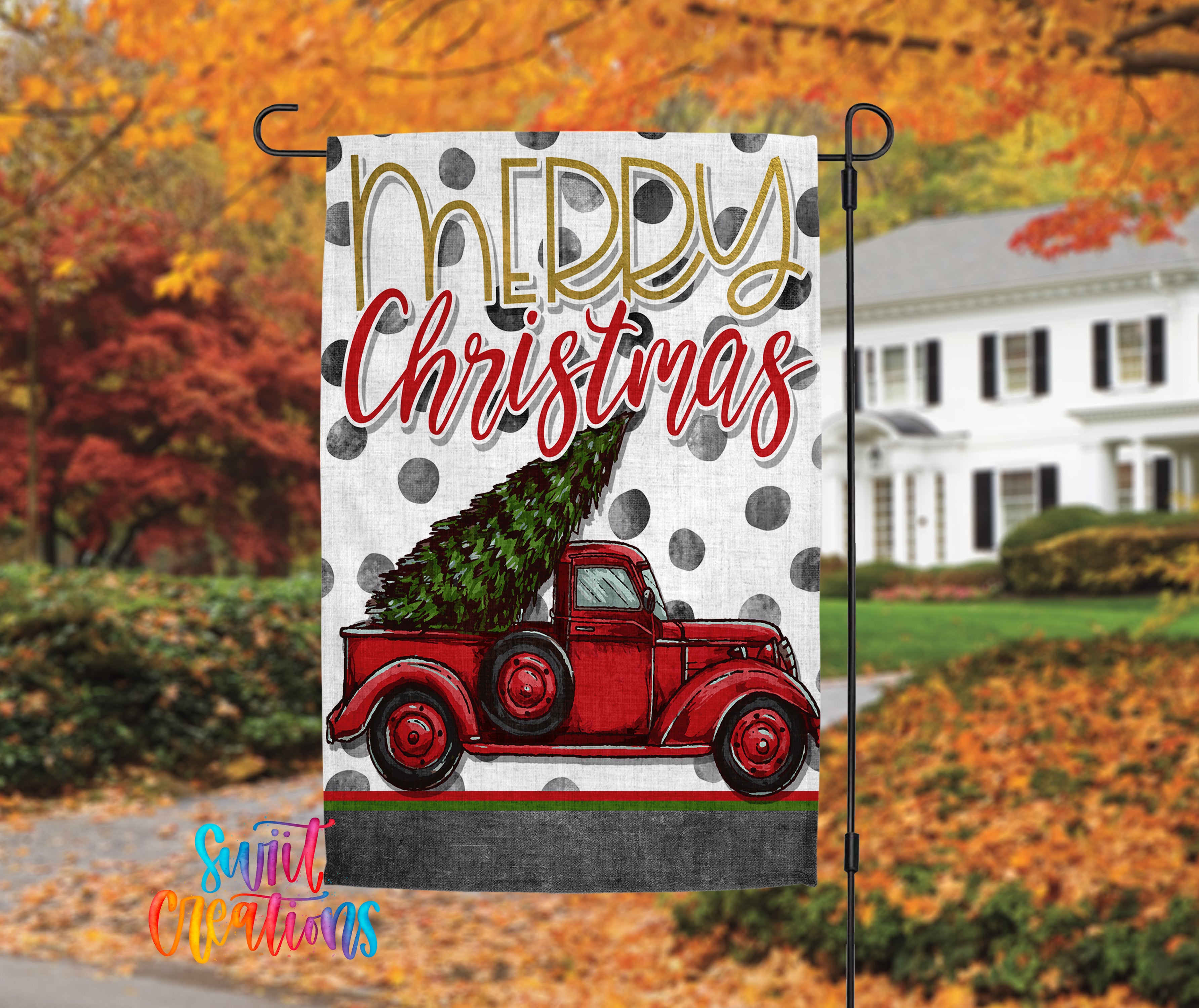 A yard sign with a red truck carrying a Christmas tree, set against a backdrop of autumn foliage.