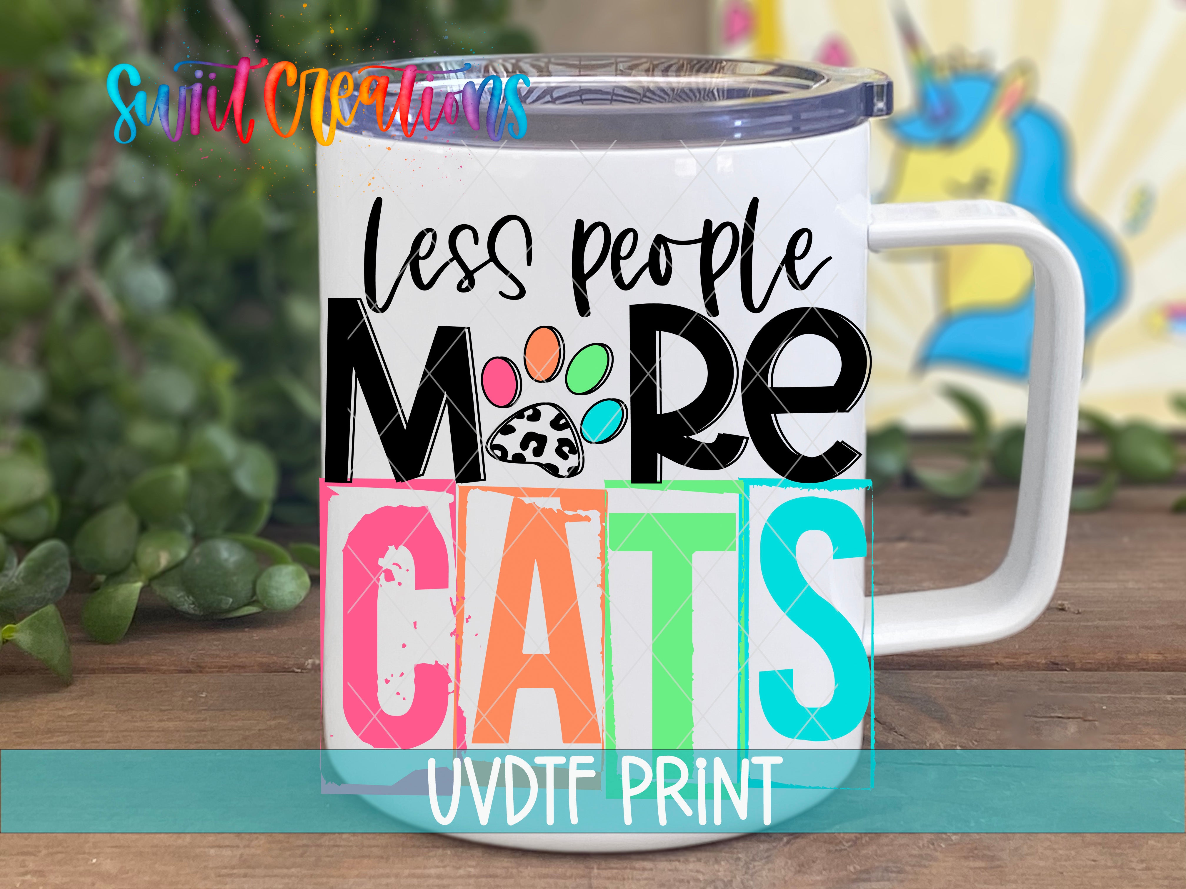 A white mug with colorful text and a paw print design, placed on a wooden surface with greenery in the background.