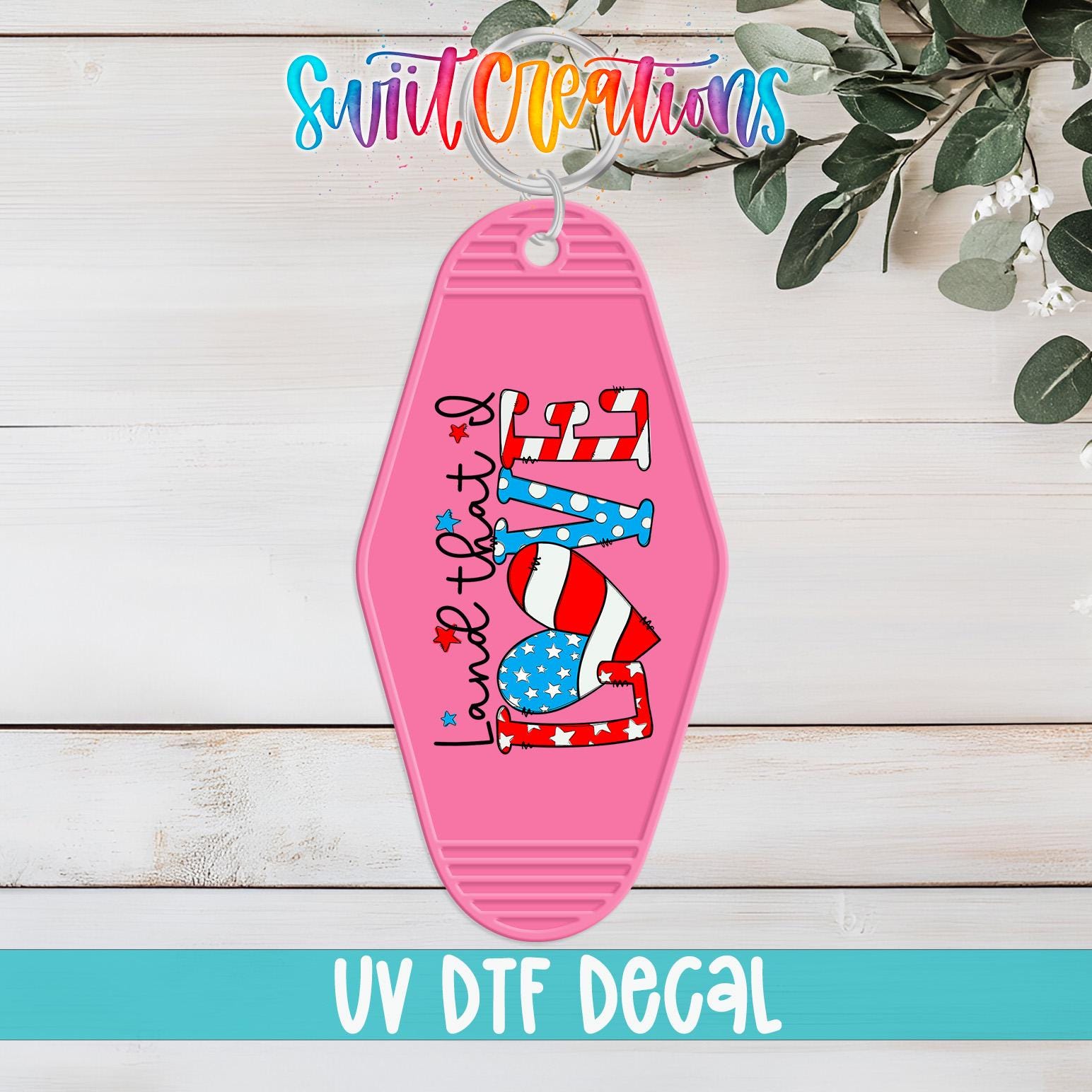 A pink keychain with a patriotic design, including an American flag and the word "LOVE", is displayed on a wooden surface.