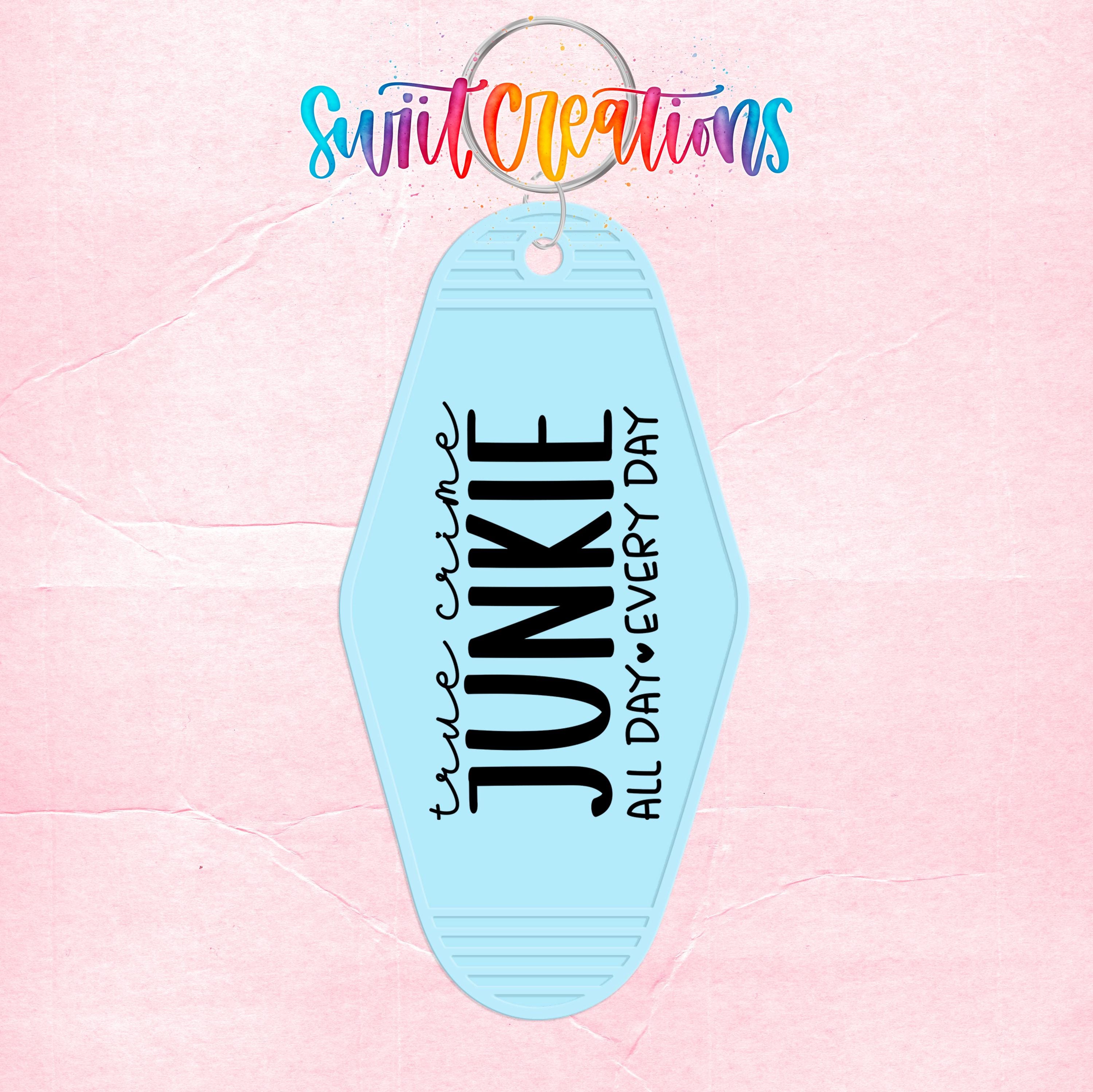 A keychain with the text "True Crime Junkie All Day Every Day" printed on it, along with a colorful, hand-drawn logo above it.