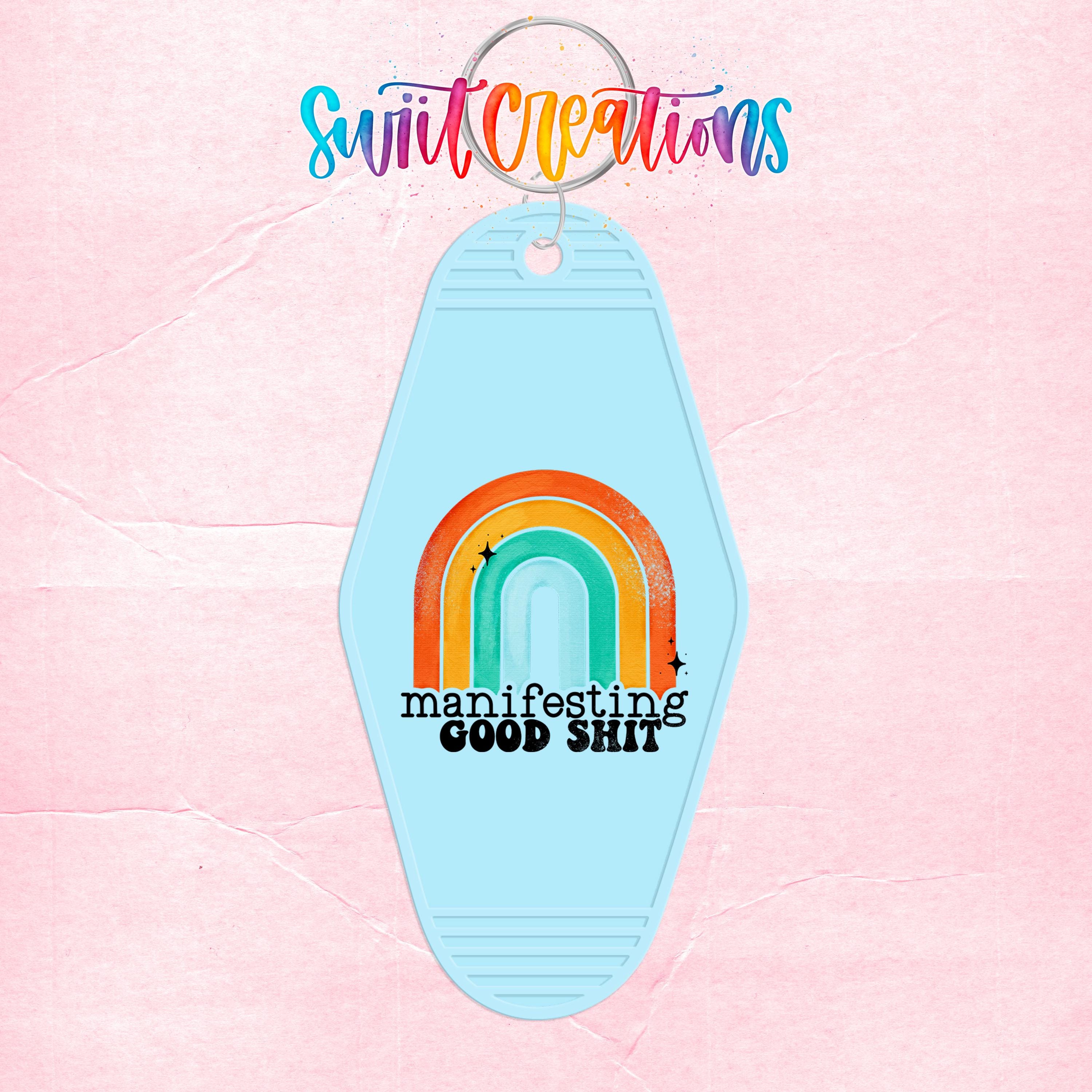 A keychain with a rainbow graphic and the text "manifesting good shit" printed on it.