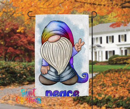A colorful gnome-like figure with a rainbow-colored hat and beard is depicted on a flag, with the word "Peace" written below it. The background features a house and trees with autumn foliage.