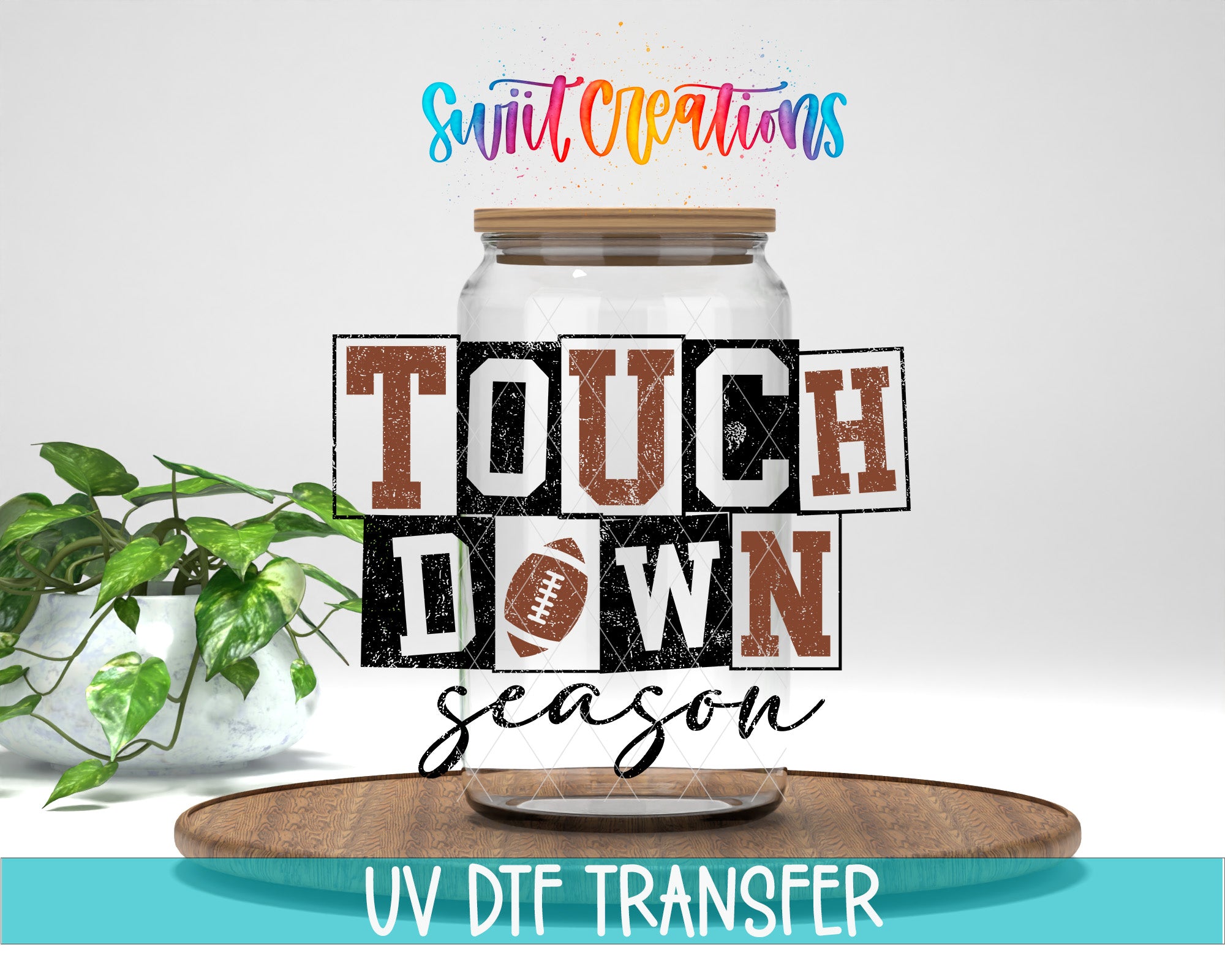 a large glass jar with the text "TOUCH DOWN" written on it, along with a plant and a wooden tray in the background.