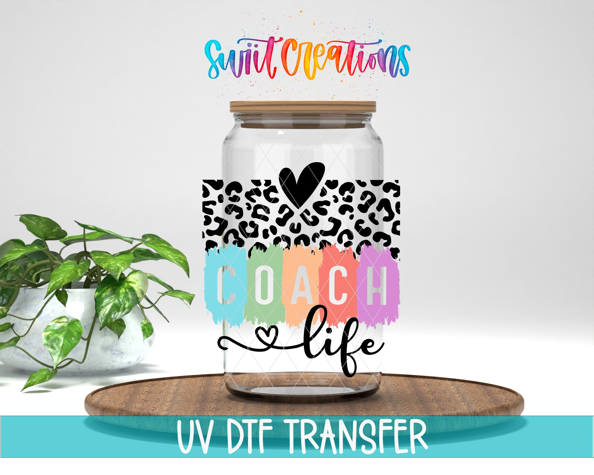 a glass jar with a leopard print design and the text "COACH life" printed on it, placed on a wooden surface. There is also a potted plant in the background.