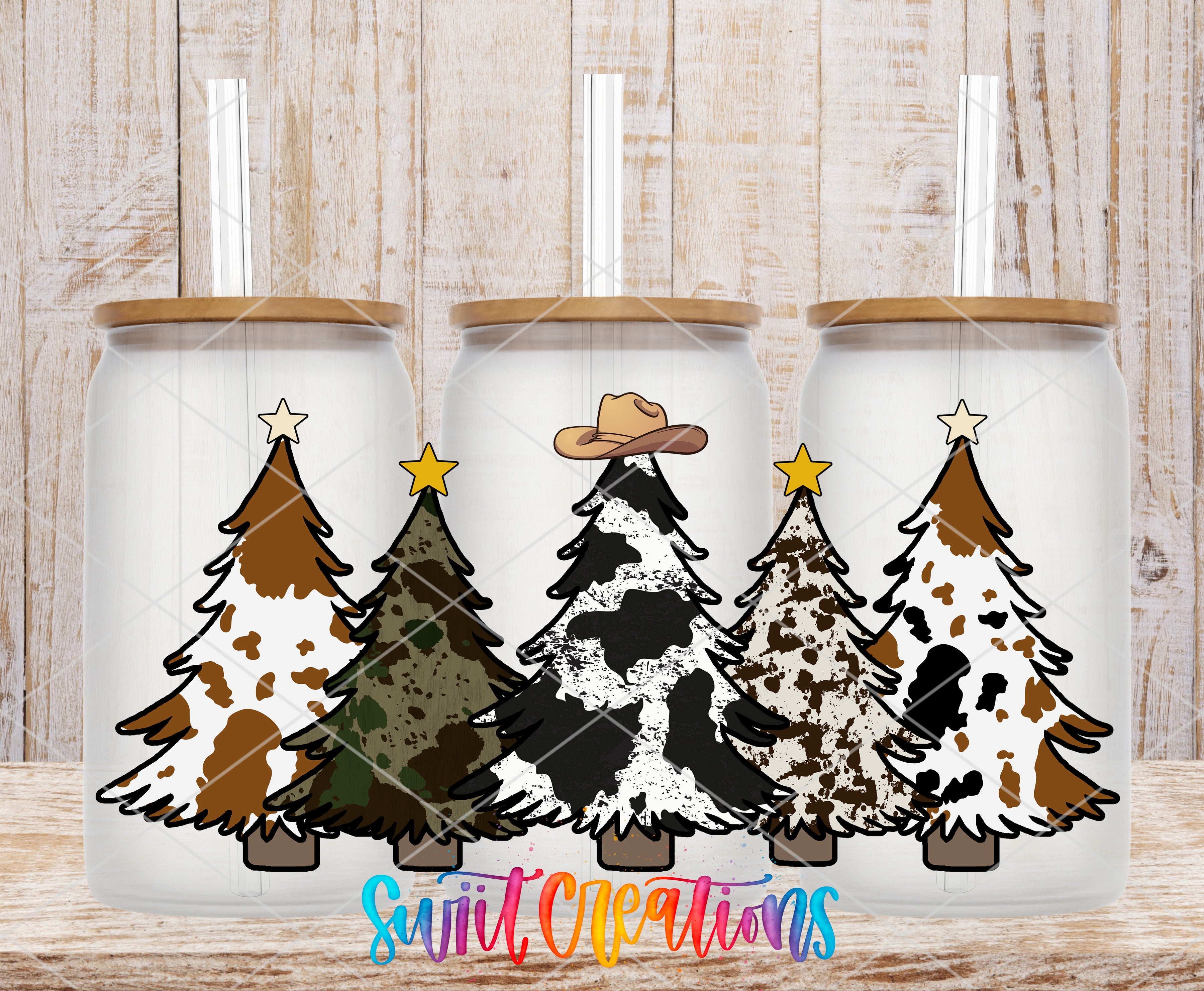 Three glass tumblers with Christmas tree designs on them, each with a straw lid, arranged in a row against a wooden background.
