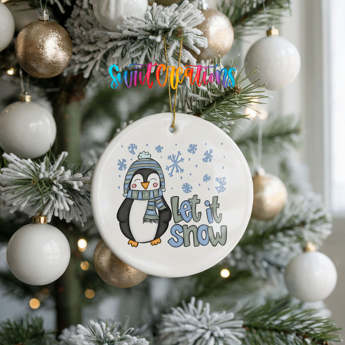A white Christmas tree decorated with ornaments, including a penguin ornament with a snowflake design and the text "Let it snow" hanging from it.