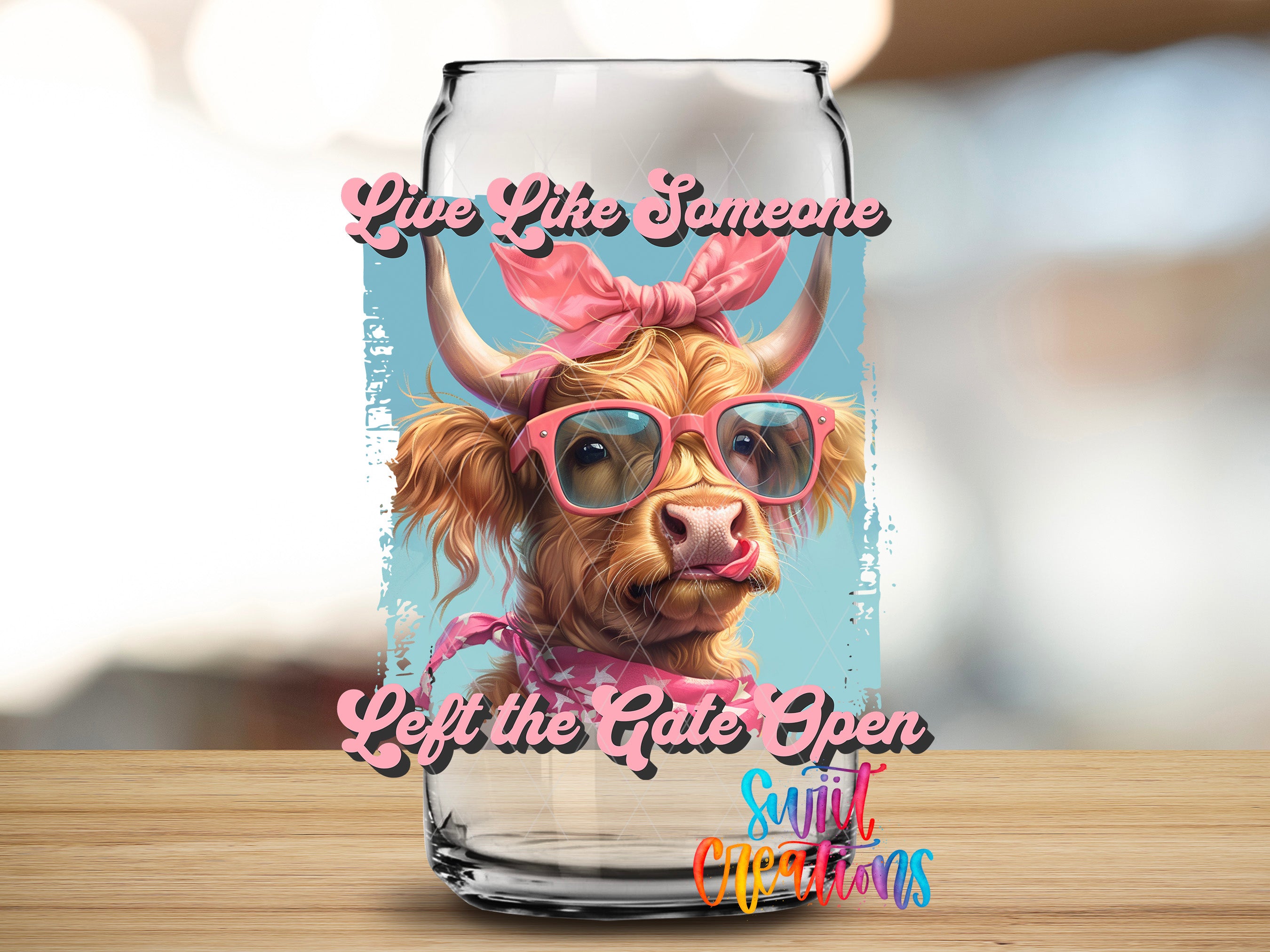 A glass can with a cow wearing sunglasses and a pink bow on its head, along with the text "Live like someone, Left the gate open, Silly occasions" printed on it.