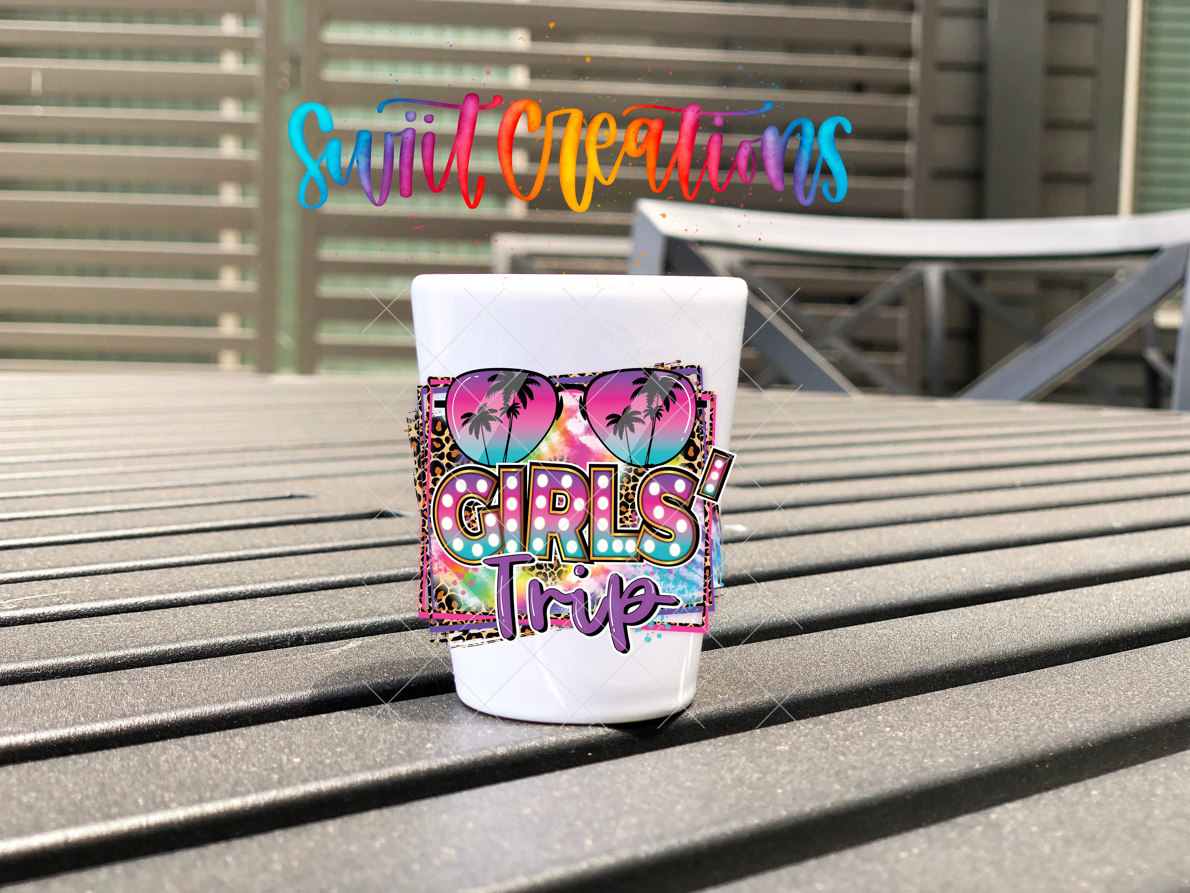 A colorful mug with the text "Girls Trip" printed on it, sitting on a wooden surface.