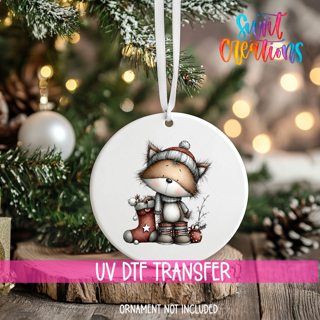 A white ceramic ornament with a cartoon image of a cat wearing a stocking cap and holding a star-shaped ornament, hanging on a Christmas tree.