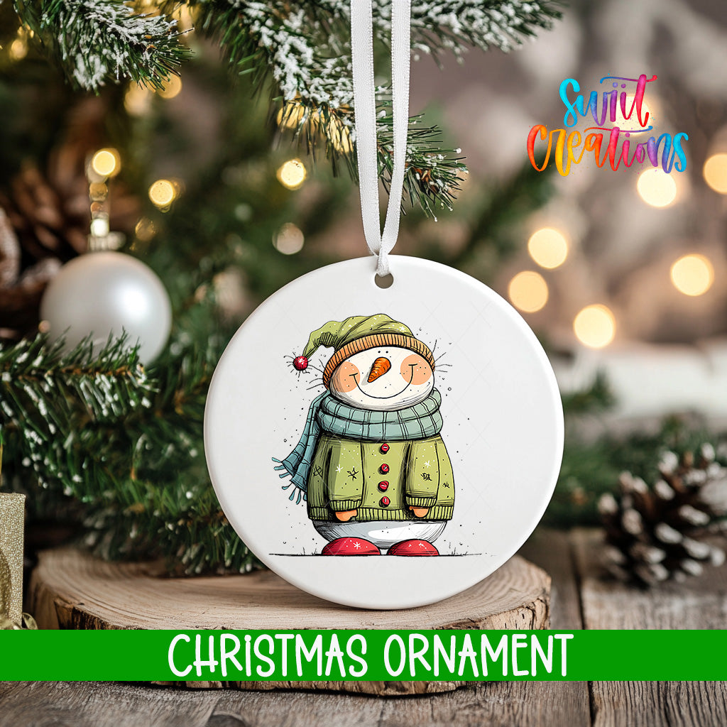 A white Christmas ornament featuring a snowman is hanging from a tree branch, with a blurred background of lights and greenery.
