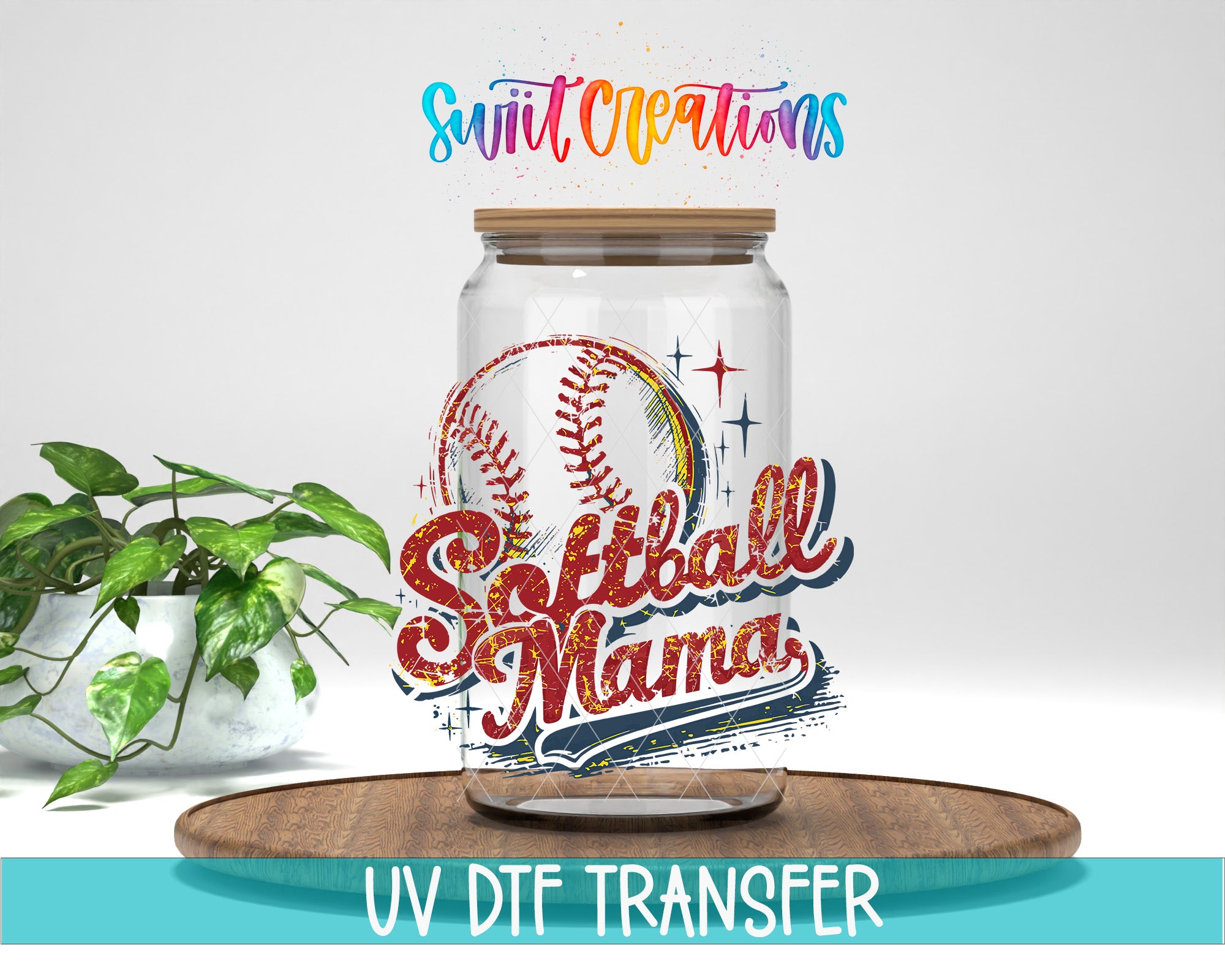 a glass jar with a baseball design, placed on a wooden surface. The jar has a wooden lid and is surrounded by a potted plant. The text "Soft Creations" is written above the jar, and "UV DFT Transfer" is written below it.