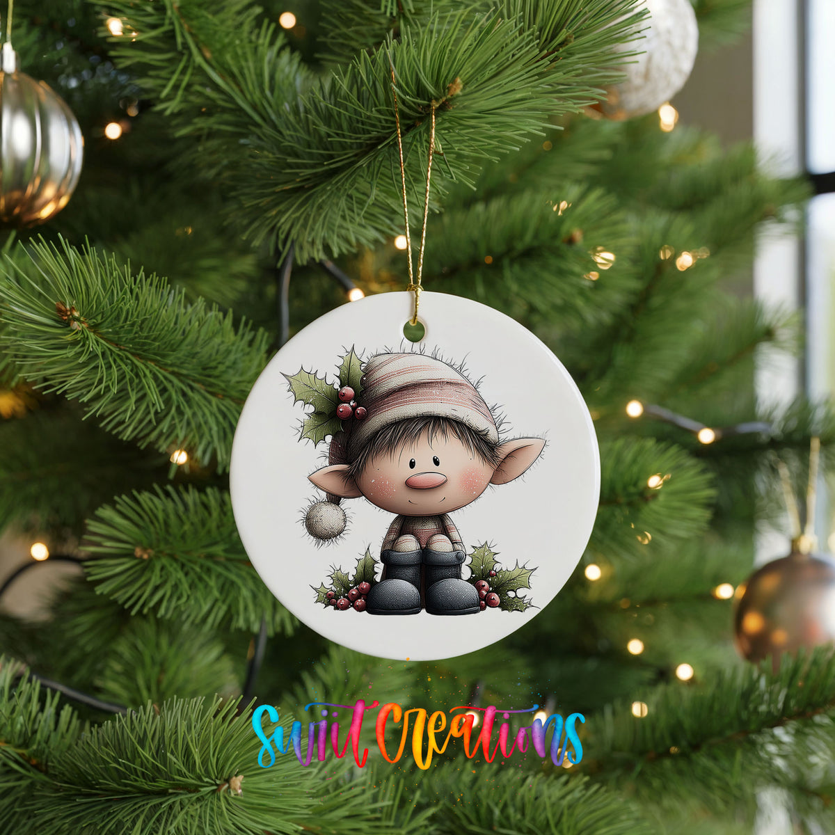 A white ornament featuring a cartoon elf sitting on a branch, surrounded by greenery and berries, is hanging from a Christmas tree.