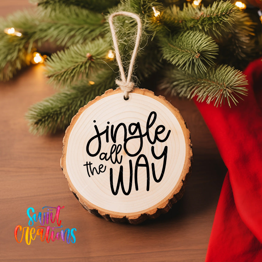 A wooden ornament with the text "Jingle all the way" hanging from a Christmas tree, surrounded by pine branches and twinkling lights.