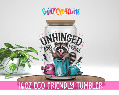 Unhinged and Feral Raccoon design on a 16 oz clear glass tumbler with bamboo lid