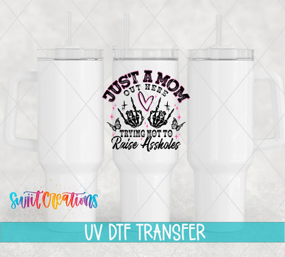 Just a Mom Trying Not To Raise Assholes UV DTF transfer applied to a white tumbler set from Swiit Creations