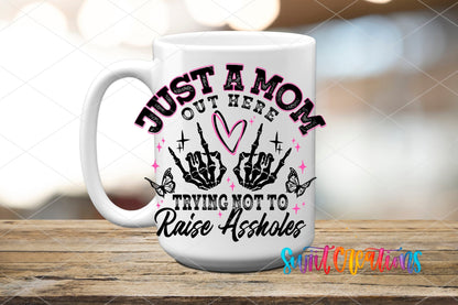 Just a Mom Trying Not To Raise Assholes UV DTF transfer displayed on a white ceramic mug from Swiit Creations